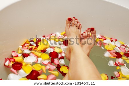 Woman legs in bath with rose petals