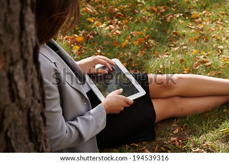Young business woman sitting with digital computer tablet  in the garden fall