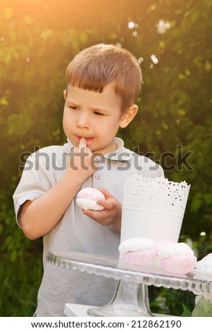 Portrait of cute kid eating marshmallow at summer day