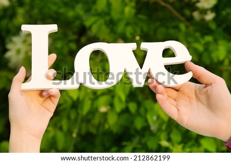 Couple hands holding love word in natural environment