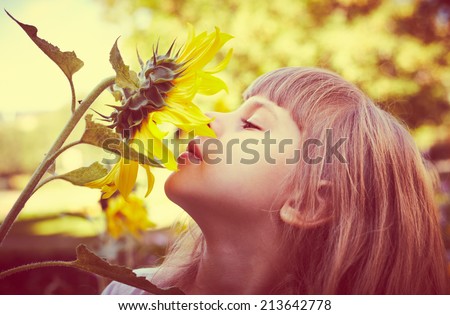 Cute child with sunflower in summer field