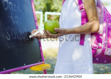 Close-up of small schoolgirl writing Back to school on blackboard, education concept