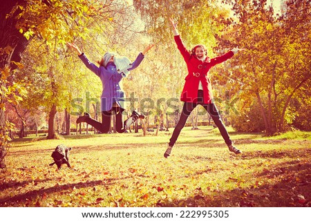 happy women jumping outside at autumn fall