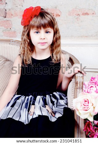 Close-up of Beautiful small girl in black dress  sitting on sofa