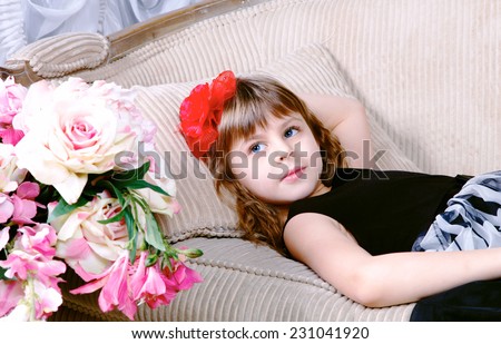 Close-up of Beautiful small girl lying on sofa near flowers