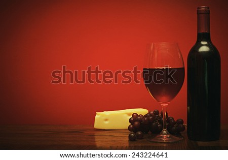 Bottle and glass of wine with red grapes and cheese a retro photo