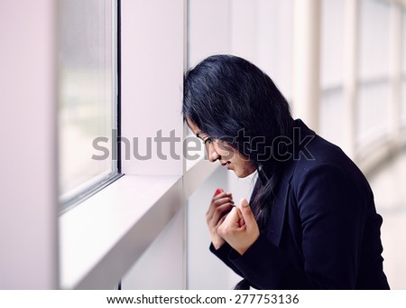 Stressed woman putting her forehead on the office wall