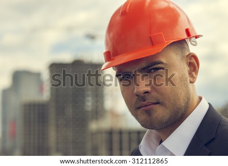 Close-up of thoughtful Worker builder  in hardhat on the background of construction