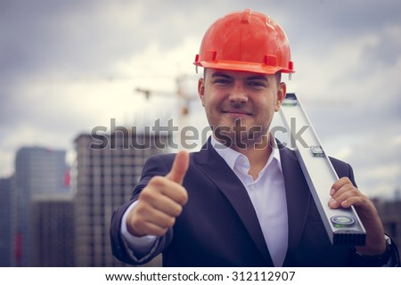 Happy worker architect showing success thumb up on the background of construction