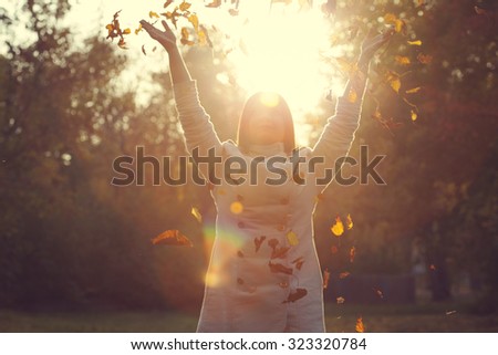 Happy woman raising hands up in autumn park - natural fall environment