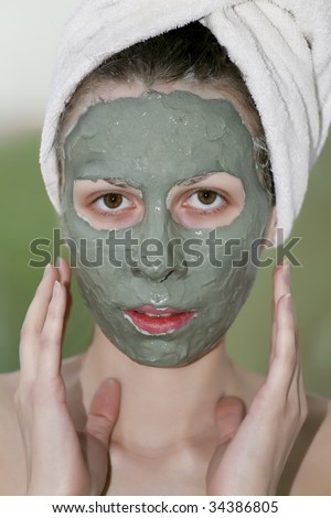 Face of female with clay mask looking at camera