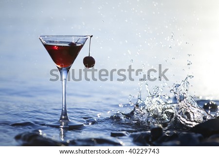 Image of martini glass with cherries in water over blue background