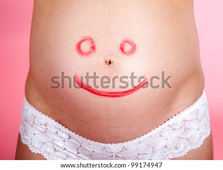 Image of face with smile painting on female belly on a rose background