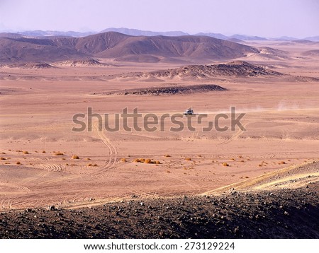 Automobile driving through desert, orange shaded sand