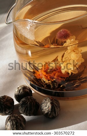 Chinese flower tea ot hardened balls which, when brewed, turn into flowers bloom. Transparent teapot. Drink. Tea flower.