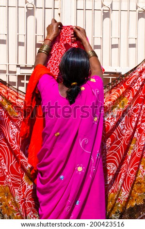 VARANASI, INDIA - MAR 2, 2013: Woman hanging sari for drying on the banks of Ganges river, Varanasi, India