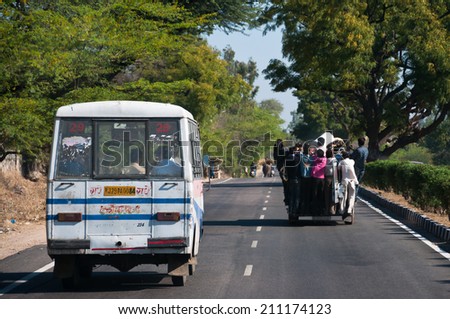 Jaipur, India - March 08, 2013: People traveling on the bus and car on the road near Jaipur