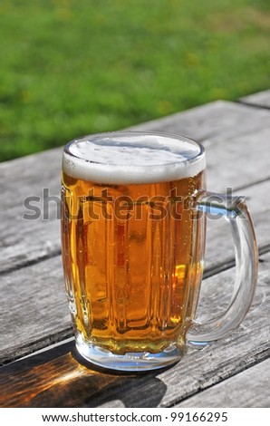 Beer mug on the old wooden table outdoor