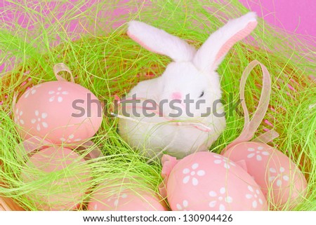 Easter eggs and rabbit with cake on lilac background