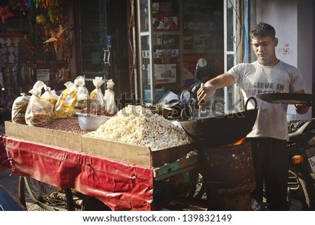 NEW DELHI - FEBRUARY 15: Man cooking and selling  India's  popular street food  - nust and popcorn  on February 15, 2013 in New Delhi, India.