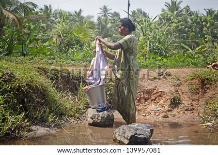 KOCHI-DECEMBER 5: An Indian woman washes her clothes on a rock in one of the canals around Kochi on December 5, 2012 in Kochi, Kerala state, India.