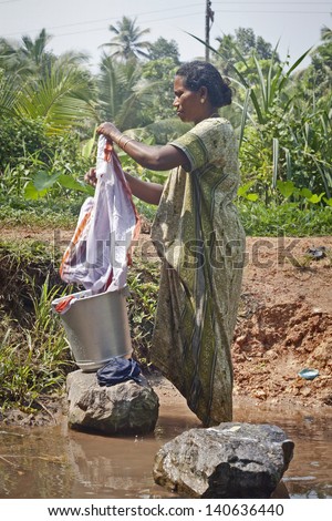 KOCHI-DECEMBER 2012: An Indian woman washes her clothes on a rock in one of the canals around Kochi on December 5, 2012 in Kochi, Kerala state, India.