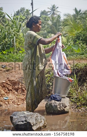 KOCHI-DECEMBER 2012: An Indian woman washes her clothes on a rock in one of the canals around Kochi on December 5, 2012 in Kochi, Kerala state, India.