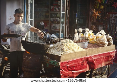 NEW DELHI - FEBRUARY 15: Man cooking and selling  India\'s  popular street food  - nust and popcorn  on February 15, 2013 in New Delhi, India.