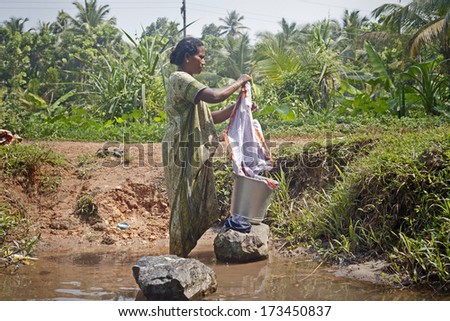 KOCHI - DECEMBER,5 2012: An Indian woman washes her clothes on a rock in one of the canals around Kochi on December 5, 2012 in Kochi, Kerala state, India.