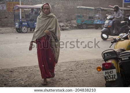 DELHI, INDIA - NOVEMBER 10: Morning on a street , poor woman with roti, at November 10, 2013 in Old Delhi, India