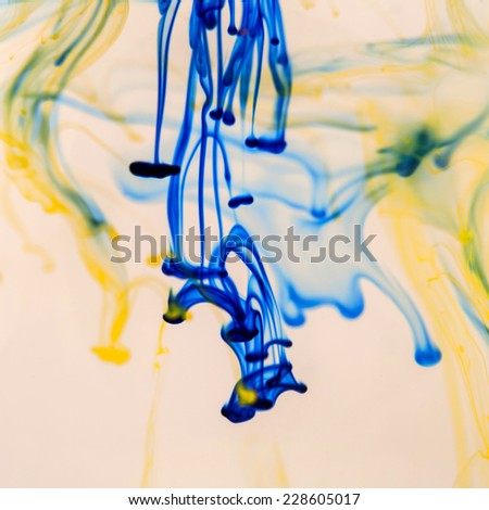 Blue and yellow liquid in water making abstract forms