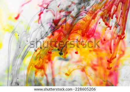 Red and yellow liquid in water making abstract forms
