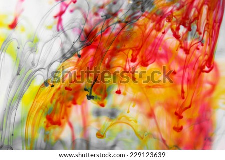 Red and yellow liquid in water making abstract forms