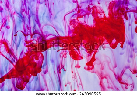 Red and violet liquid in water making abstract forms