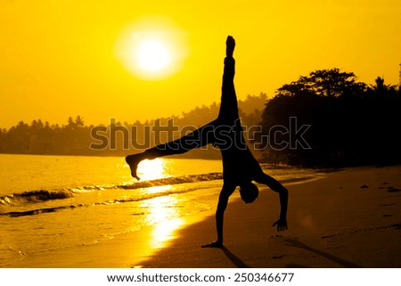silhouette of young man standing on his hands taken in sri-lanka on the sunrise