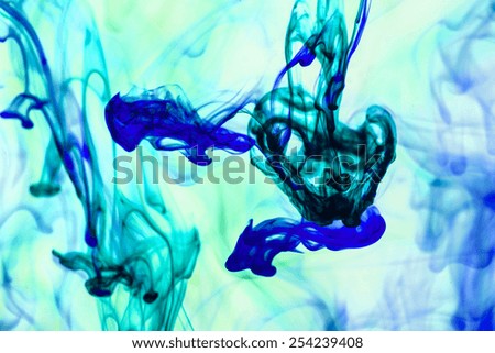 Blue and green  liquid in water making abstract forms