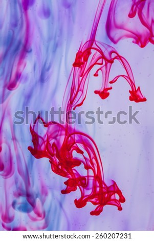 Red and violet liquid in water making abstract form