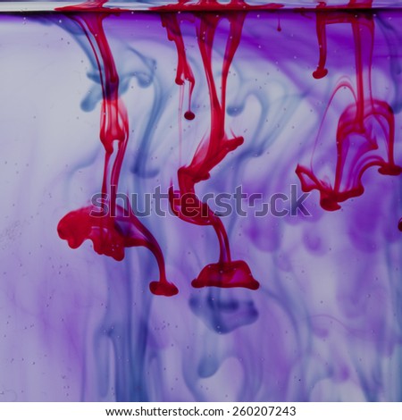 Red and violet liquid in water making abstract form