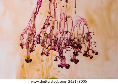 Yellow and violet liquid in water making abstract forms