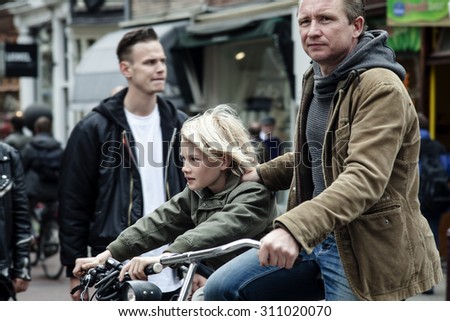 AMSTERDAM, NETHERLANDS - MAY 9:  Father with son riding bicycles in historical part in Amsterdam, Netherlands on May 9, 2015