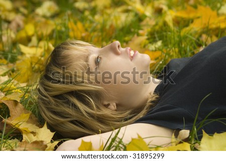 Young girl lying on the grass in the autumn leaves