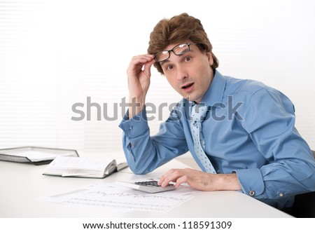 Shocked businessman with calculator at his office