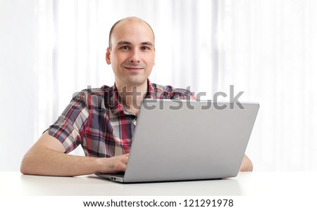 Portrait of a happy young man using a laptop. Indoor