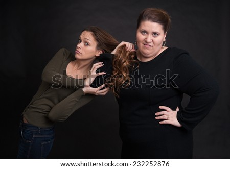 two angry women fighting over black background