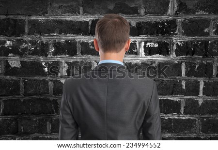 Back view of Businessman looking at brick wall