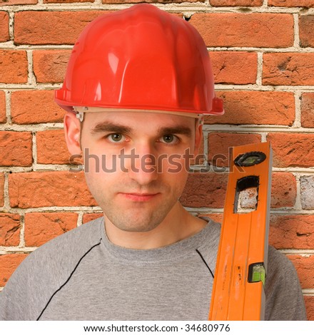 handyman with red hat and a brick wall as background