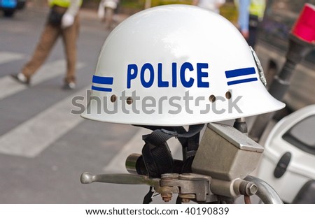 Police helmet on motorcycle handlebars with traffic cops in the background