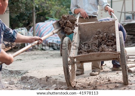 A worker shovels dirt into a wheelbarrow in Shanghai, China