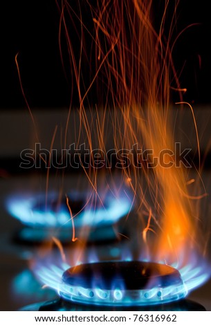 sparks and flames above gas stove burning with blue flames