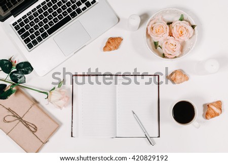 Workspace with diary, pen, vintage white tray, pink rose, croissants and coffee on white background. Top view, flat lay